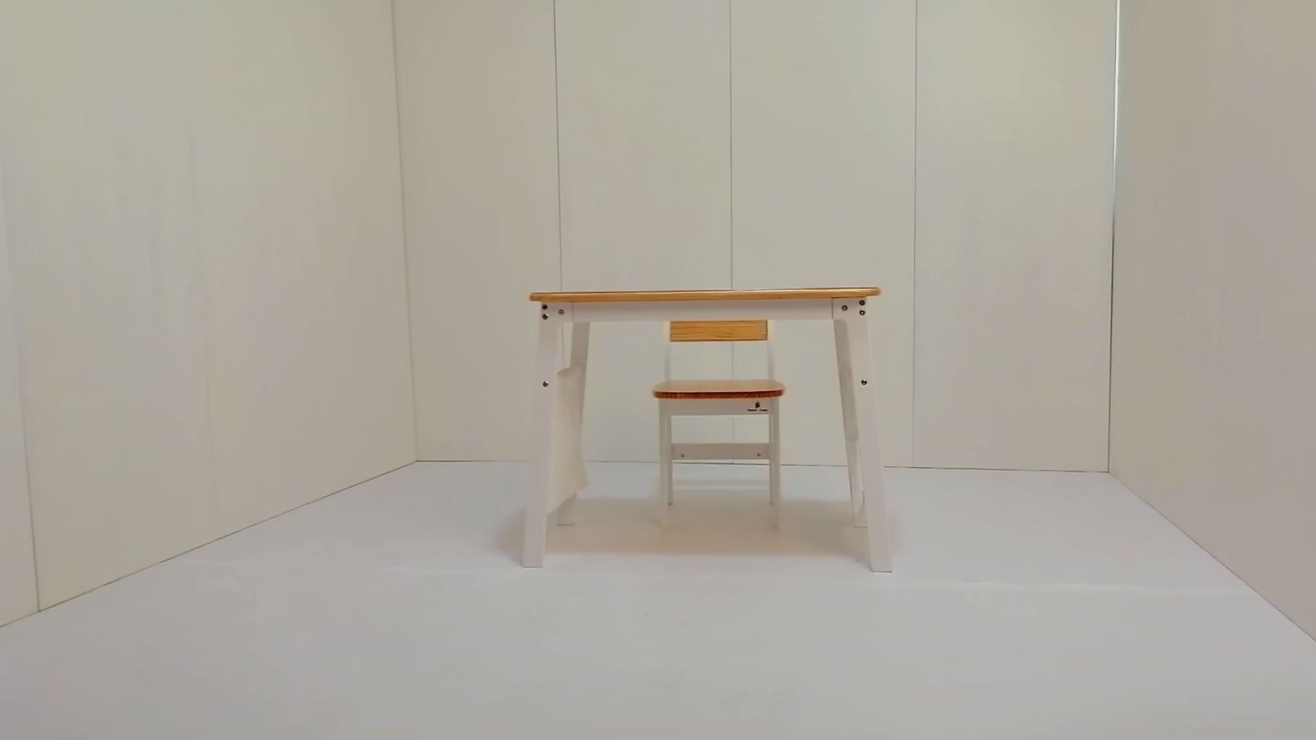 Smiling child drawing at 'My First Desk' with storage bags and PVC mat. Solid wood construction with rounded safety corners.